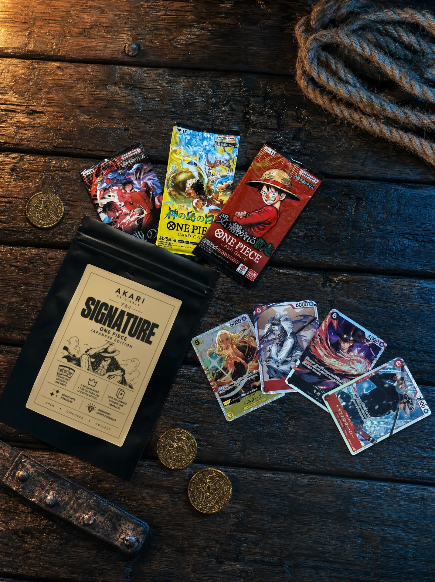 Sachet Akari Signature One Piece avec trois boosters officiels japonais et quatre cartes (Stussy, Sabo, Trafalgar Law), sur table en bois avec cordage et pièces dorées
